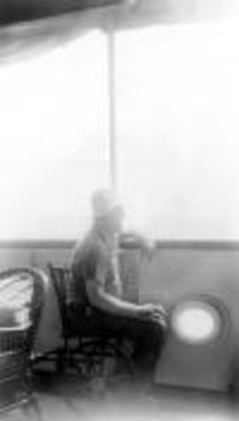 An old photo of President Franklin D Roosevelt,sitting on a boat in a wheelchair, looking out over the side toward the sea.